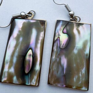 May include: A pair of rectangular drop earrings featuring iridescent abalone shell inlays with swirling shades of brown, green, and purple. The rectangular shell pieces are set in thin metal frames and attached to silver-toned metal fishhook ear wires.