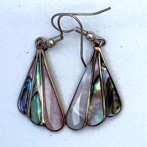 May include: A pair of dangle earrings featuring a fan-shaped metal frame. Each earring contains three inlaid segments of iridescent abalone shell and smooth, pale pink mother-of-pearl, suspended from silver-toned metal ear wires.