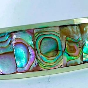 May include: A silver-toned bracelet with iridescent abalone shell inlays. The rectangular shell pieces display a range of colors, including blues, greens, and purples. The bracelet has a polished finish and a classic design.
