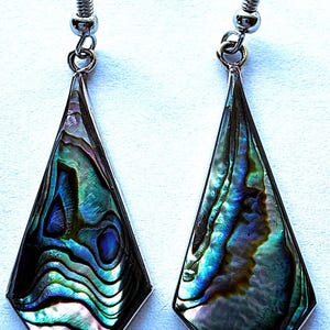 May include: A pair of dangle earrings featuring kite-shaped abalone shell inlays set in silver-toned metal frames. The iridescent shell displays swirling patterns of deep blue, green, and purple hues. Each earring hangs from a silver-toned hook.