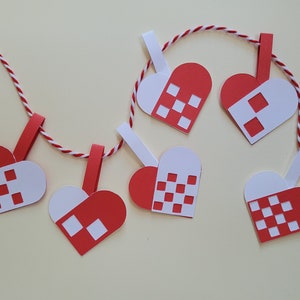 Puede incluir: Una cadena de corazones de papel rojo y blanco con un patrón a cuadros, colgando de una cuerda blanca. Los corazones están unidos con pinzas de la ropa.