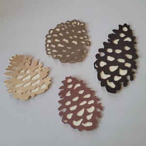 May include: Four paper pine cone cutouts in different colours and sizes. The pine cones are brown, tan, and a reddish brown.