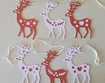 May include: A string of six red and white reindeer paper cutouts with white stars, hearts, and dots. The reindeer are connected by a white string.