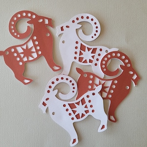May include: Four paper cutouts of stylized rams with geometric patterns. The rams are in shades of red and white.