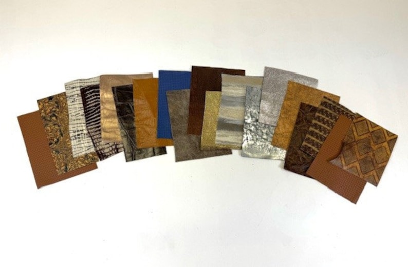 May include: A collection of 16 different leather swatches in various colors and textures, including brown, tan, gray, and blue. The swatches are arranged in a semi-circle on a white background.
