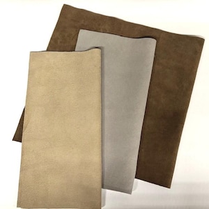 May include: Three pieces of suede fabric in different colors: brown, beige, and gray.