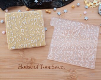May include: A square cookie embossed with a white celebration pattern featuring champagne bottles, glasses, balloons, and musical notes, alongside a matching clear acrylic stamp with the same design and the text House of Toot Sweet.