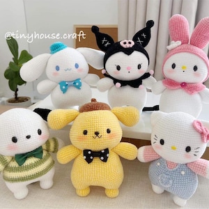 May include: A collection of seven crocheted character dolls, including a white dog with a green and yellow striped shirt, a yellow dog with a black bow tie, and a white cat wearing blue overalls. Other characters include a white bunny with pink ears and a black and white character with a black hat.