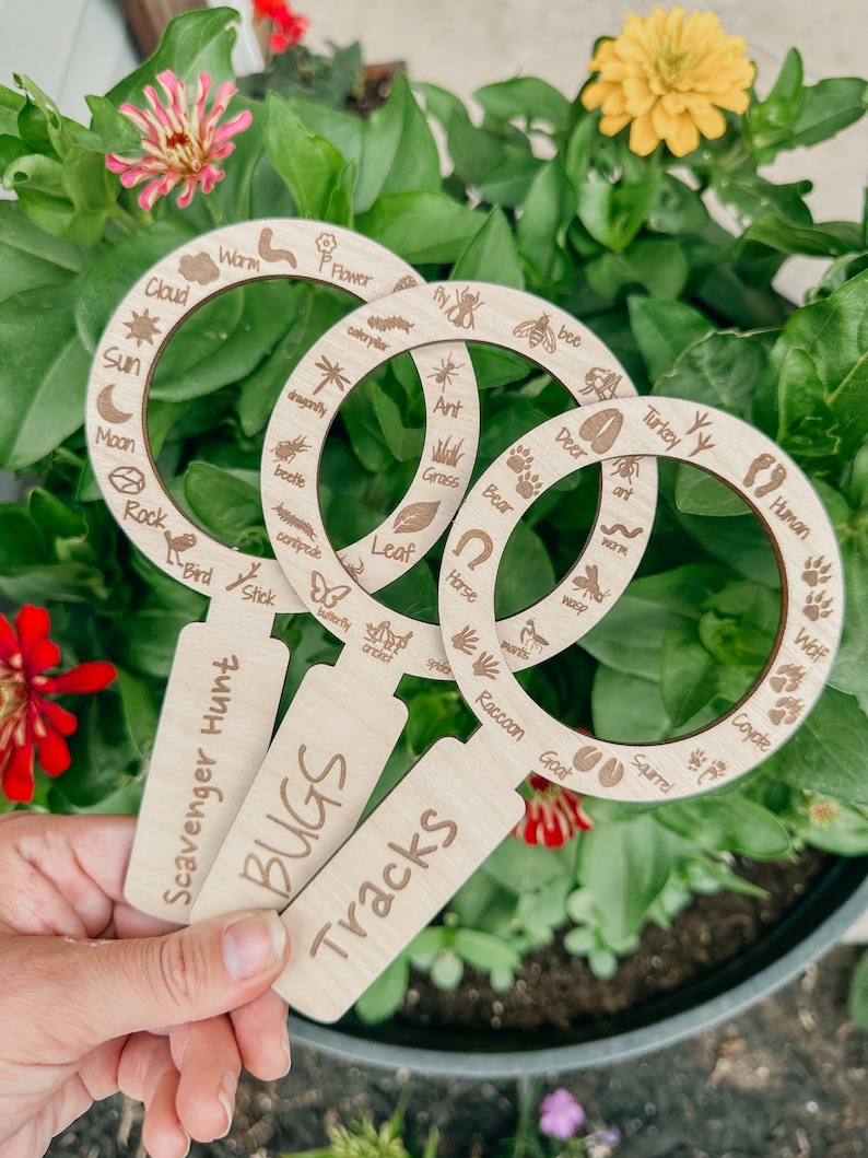 May include: Three wooden nature scavenger hunt tools with magnifying glass rings. The rings are labeled with different animals, insects, and plants. The tools are labeled "Scavenger Hunt", "Bugs", and "Tracks".