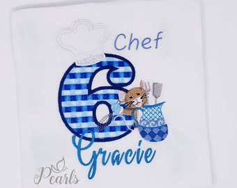 May include: A white embroidered shirt with a blue and white checkered number 6, a chef's hat, a cartoon mouse holding a spoon and a pitcher, and the text "Chef Gracie".