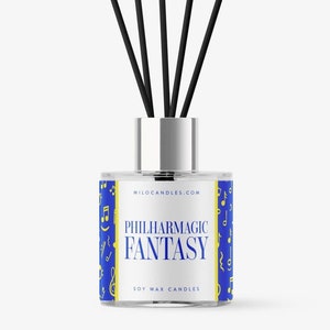 May include: A glass diffuser bottle with a silver cap and black reeds. The label reads "PHILHARMAGIC FANTASY" in blue text on a blue background with musical notes. The product is soy wax candles.