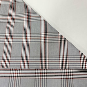 May include: A close-up of a gray and white plaid fabric with red and black stripes. The fabric is folded in half, and the top half is white. The text #08G/Baldwin is printed in black on the white background.