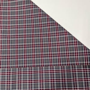 May include: A close-up of a gray and burgundy plaid fabric with white stripes. The fabric is folded in half, with the top half folded over the bottom half. The fabric is labeled with the number "#34/Rose".