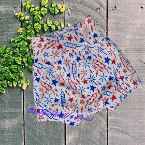 May include: White fabric with a red, white, and blue pattern of stars, fireworks, and sparklers.