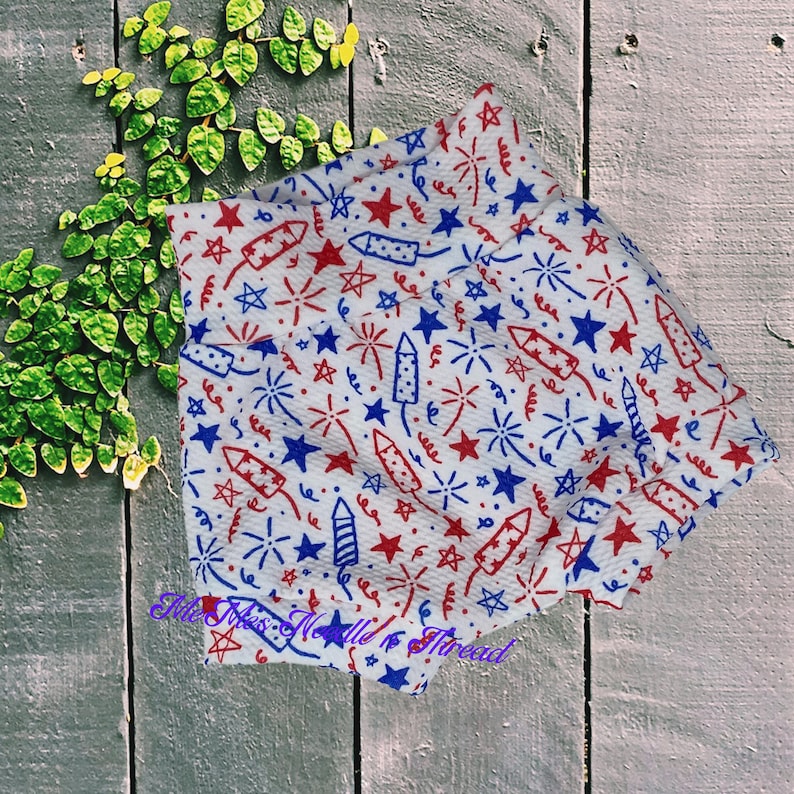 May include: White fabric with a red, white, and blue pattern of stars, fireworks, and sparklers.