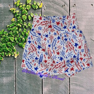 May include: White fabric shorts with a red, white, and blue firework and star pattern.