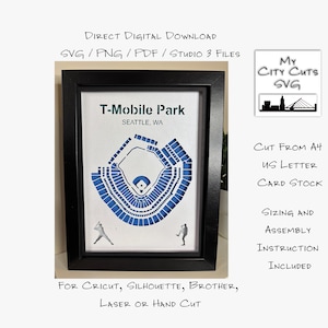 May include: Framed artwork depicting a blue and white illustration of T-Mobile Park in Seattle, WA. The stadium design includes a baseball diamond and seating areas. The artwork is in a black frame and includes the text: "T-Mobile Park Seattle, WA."