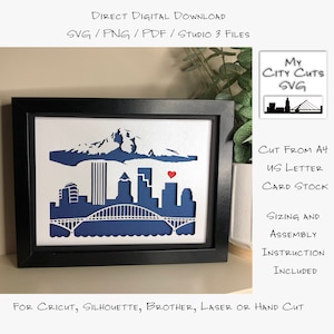 May include: A framed paper craft of the Portland, Oregon skyline with a red heart over the city. The craft is cut from blue and white cardstock and is ready to be assembled. The image includes the text "My City Cuts SVG", "Cut from A4 US Letter Card Stock", "Sizing and Assembly Instruction Included", and "For Cricut, Silhouette, Brother, Laser or Hand Cut".