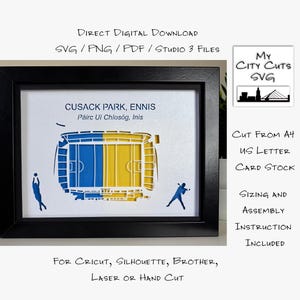 Op de afbeelding: Ingelijste papieren kunst van Cusack Park in Ennis, Ierland, met blauwe en gele stadiondetails. Bevat tekst: "Cusack Park, Ennis" en "My City Cuts SVG". Het kunstwerk is gesneden uit A4- of US Letter-karton.