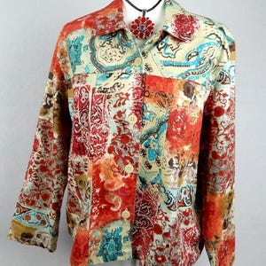 May include: A long-sleeved button-down jacket featuring a vibrant patchwork pattern in shades of red, orange, turquoise, and cream. The garment has a classic collar, a front button closure, and a complex floral and paisley print throughout.