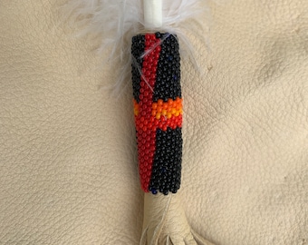 Una pluma de águila de imitación con plumas y flecos adornados con cuentas.