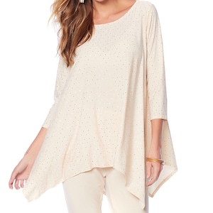 May include: Cream-colored, three-quarter sleeve top with a scoop neck and a unique asymmetrical hemline. The fabric is dotted with small, metallic accents. The top is paired with cream-colored pants, creating a monochromatic look.