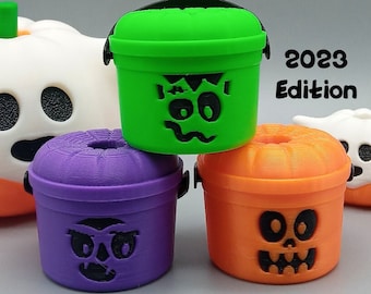 Könnte beinhalten: Drei Halloween-thematische McDonald's McCafe Eimer Strohhalm-Topper. Die Eimer sind grün, lila und orange und zeigen verschiedene gruselige Gesichter. Der Text "Bcc Bucket Straw toppers 2023 Edition" ist über den Eimern sichtbar.