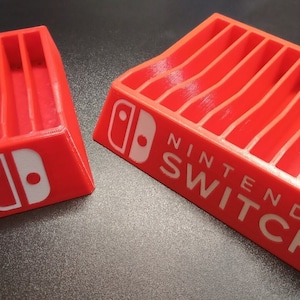 May include: Red plastic Nintendo Switch game cartridge storage case with 10 slots. The case has a white Nintendo Switch logo and the words "Nintendo Switch" printed on the front.