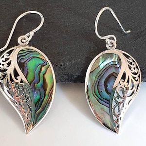 Könnte beinhalten: Ein Paar silberne Ohrringe mit einem tropfenförmigen Abalone-Muschel-Design. Die Muschel ist irisierend in Grün-, Blau- und Violetttönen.