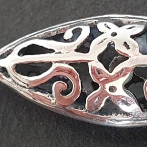 May include: Silver earring with a delicate, openwork design featuring a floral motif. The earring is marked "925" indicating it is made of sterling silver.