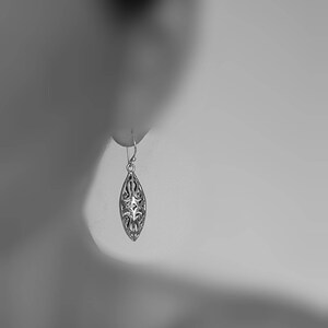 May include: A silver filigree dangle earring with a teardrop shape.