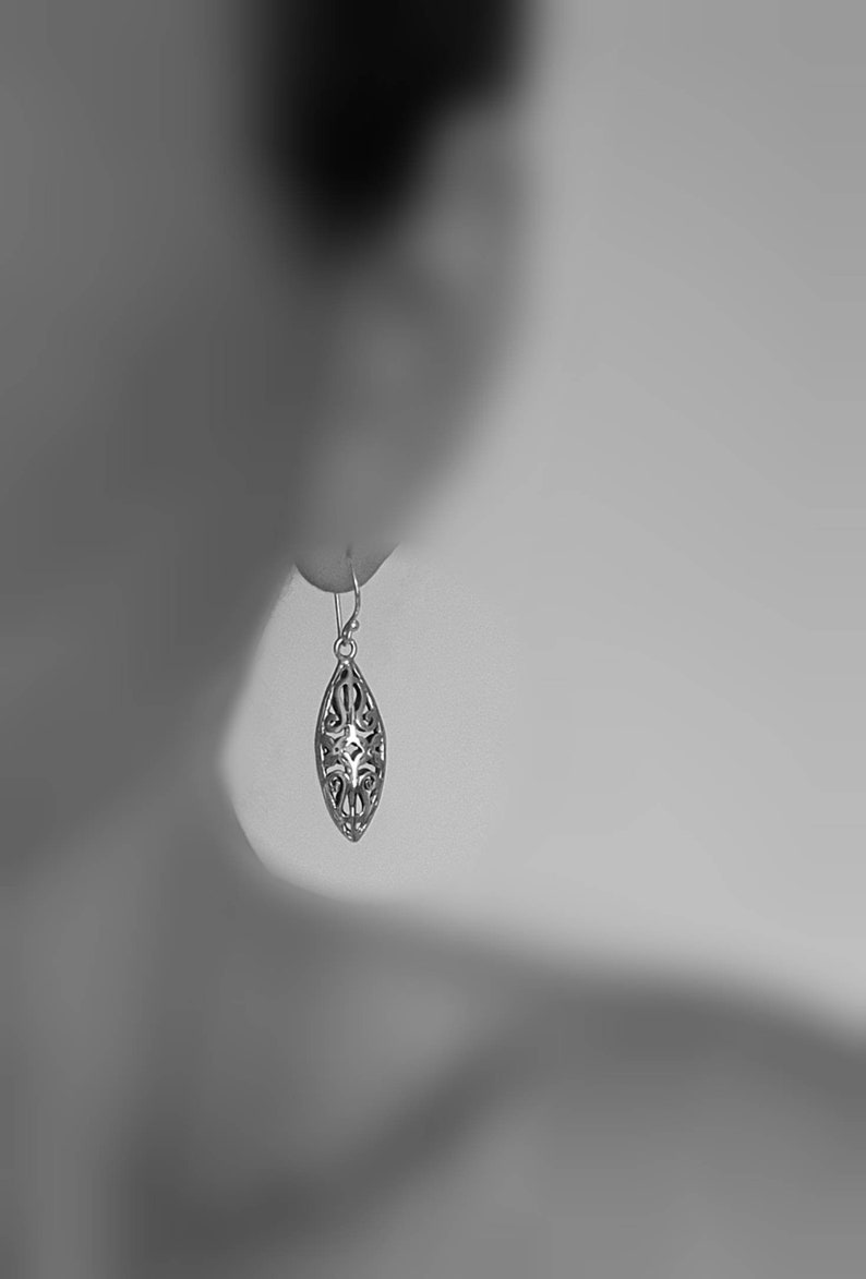 May include: A silver filigree dangle earring with a teardrop shape.