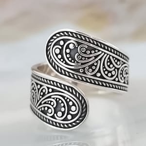 Op de afbeelding: Een zilveren ring met een zwierig, paisley-achtig ontwerp. De ring is open en verstelbaar.