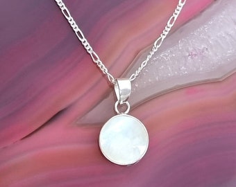 Op de afbeelding: Een zilveren ketting met een ronde witte parelmoer hanger.