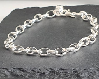 Puede incluir: Un brazalete de cadena de plata con cierre de mosquetón. El brazalete está hecho de eslabones ovalados.
