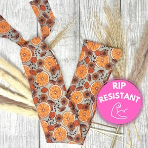 May include: A gray headband with a repeating pattern of orange slices and brown flowers. The headband is made of a rip-resistant material. The text "RIP RESISTANT" is in a pink circle.