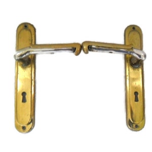 Op de afbeelding: Een paar antieke messing deurgrepen met een sleutelgat en een zilveren hendel. De grepen zijn in goede staat en hebben een klassiek ontwerp.