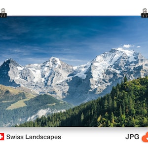 Puede incluir: Un póster de los Alpes suizos, con picos nevados contra un cielo azul claro. La imagen muestra densos bosques verdes y colinas. El texto "Swiss Landscapes" es visible en la parte inferior izquierda.