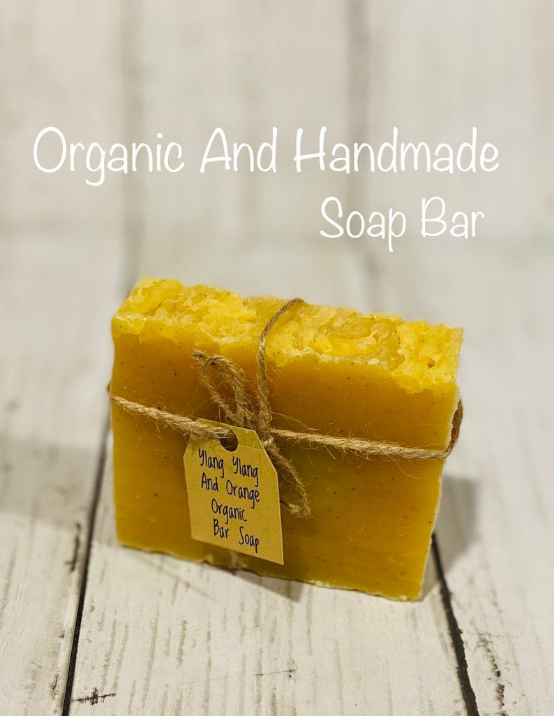 Pu&ograve; includere: Una saponetta biologica fatta a mano con un'etichetta di carta marrone che recita "Ylang Ylang And Orange Organic Bar Soap". Il sapone &egrave; di colore giallo brillante ed &egrave; legato con uno spago.