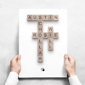 May include: A white rectangular print featuring wooden letter tiles arranged in a crossword style. The names Austin, Rosie, and Will are connected by the word Schollar. A small black heart icon is positioned at the bottom center of the page.
