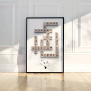 May include: A framed wall art print featuring a crossword puzzle arrangement of wooden letter tiles spelling out the names Jemma, Noreen, Jim, Chris, Dylan, William, Georgia, and Nicola. The word Family is printed below with a small heart icon.