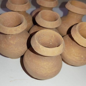 Peut inclure: Ensemble de petits pots en terre cuite non émaillés. Les pots ont une base arrondie et un bord évasé, de couleur naturelle et terreuse. Certains pots ont une pièce de bord assortie séparée. L'arrangement suggère un thème artisanal ou de décoration intérieure.