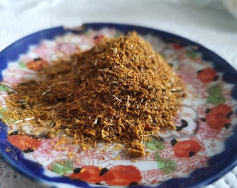 May include: A small pile of dried herbs and spices on a blue and white patterned plate. The herbs and spices are a mixture of brown, yellow, and orange.