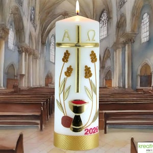 Könnte beinhalten: Eine weiße Säulenkerze mit goldenem Kreuz, Weizenähren und Kelchdesign. Die Kerze trägt die griechischen Buchstaben Alpha und Omega und das Jahr 2026 in Rot. Der Sockel ist mit einem goldenen Band verziert. Die Kerze ist angezündet.