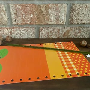 Pode incluir: Um projeto de artesanato com papel estampado laranja, amarelo e vermelho, folhas verdes, um limpador de cachimbo verde e fechos de pl&aacute;stico brancos.