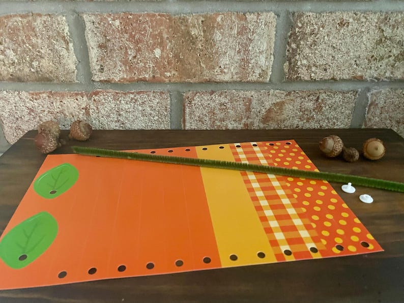 Pode incluir: Um projeto de artesanato com papel estampado laranja, amarelo e vermelho, folhas verdes, um limpador de cachimbo verde e fechos de pl&aacute;stico brancos.