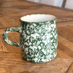 Vintage Roseville Henn Art Pottery grön svampmugg med ett grönt stänksvampmönster på en vit bas