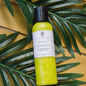 Puede incluir: Una botella amarilla de limpiador facial iluminador de cúrcuma y lemongrass de Owl & Lily Apothecary. La botella está etiquetada con el nombre del producto, los ingredientes y las instrucciones de uso. Está hecha a mano con ingredientes naturales y es adecuada para todo tipo de piel.
