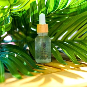 May include: A clear glass bottle with a wooden cap and dropper. The bottle contains a face serum with the text "Owl & Lily Apothecary Sea Serum Sea Kelp & Algae Extracts Face Serum" on the label.