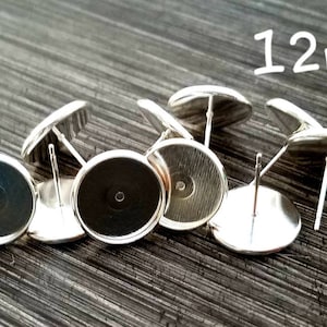 May include: Silver-toned earring posts with flat, round bases. The image shows several earring posts, each with a post for insertion and a flat, circular surface for attaching decorative elements. The text "12mm" is visible in the image.